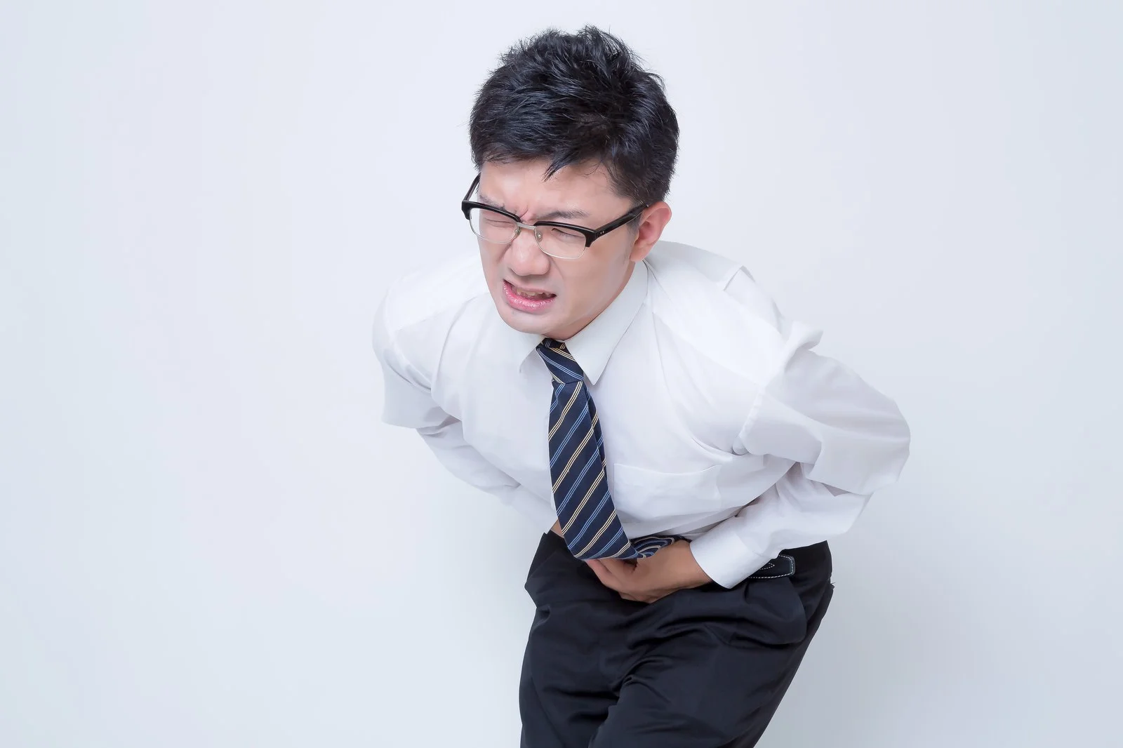 腹痛でおなかを抑える男性の写真