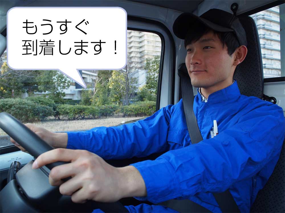 トラックドライバーの運転手の写真に「もうすぐ到着します」の文字が書かれた写真